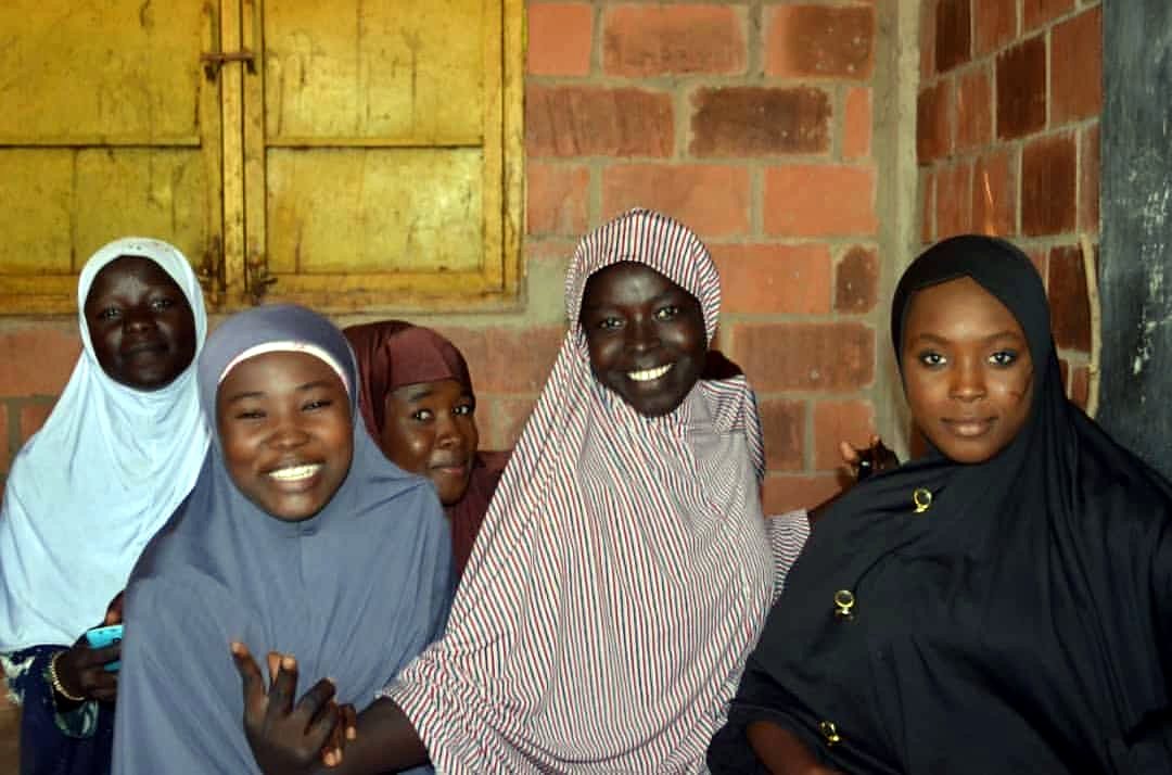 Children smiling through a classroom window